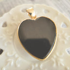 Texture detail of the opaque jet black onyx heart, polished to a high shine and feeling cool to the touch.