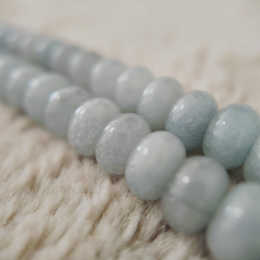 A macro shot detailing the beautiful, natural white "floating flowers" (inclusions) within the polished, pale blue stones, a sign of their authentic, natural origin.