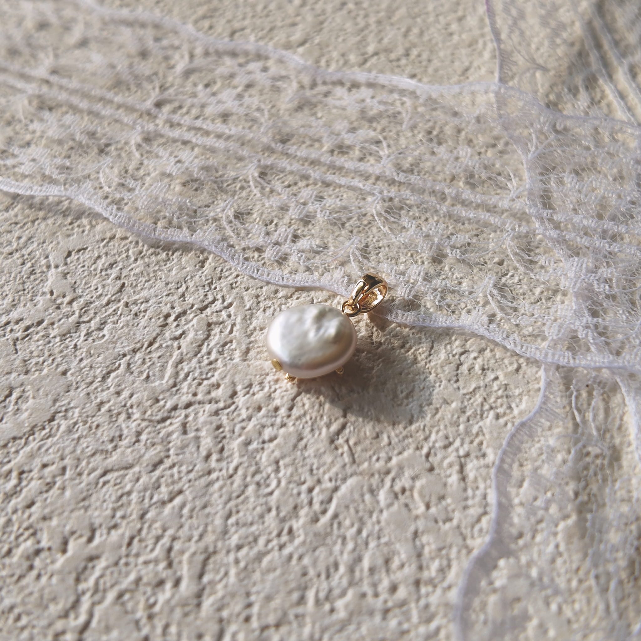 The reverse side of the "Ocean's Relic" pearl charm, showing the clean assembly and the natural, organic shape of the freshwater pearl.