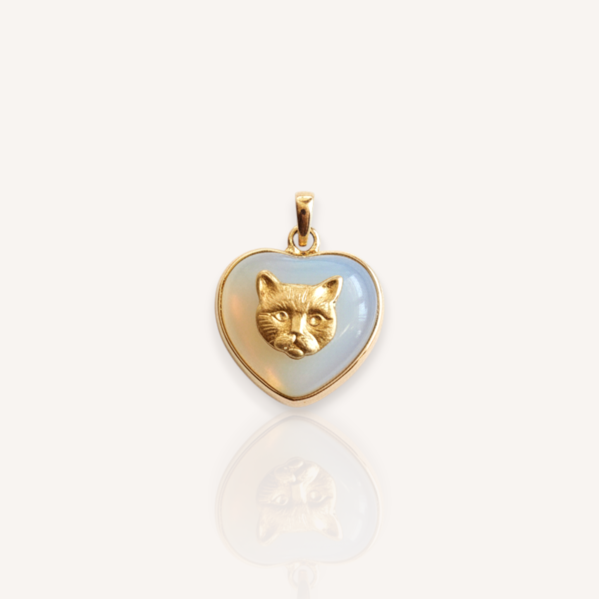 Front view of The Opaline Kitten pendant featuring a color-shifting Opalite heart with a vintage brass kitten head.
