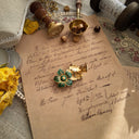 A macro shot detailing the immaculate, smooth surface of the green enamel and the rich texture of the gold-tone fronds on this piece of high-quality unsigned jewelry.