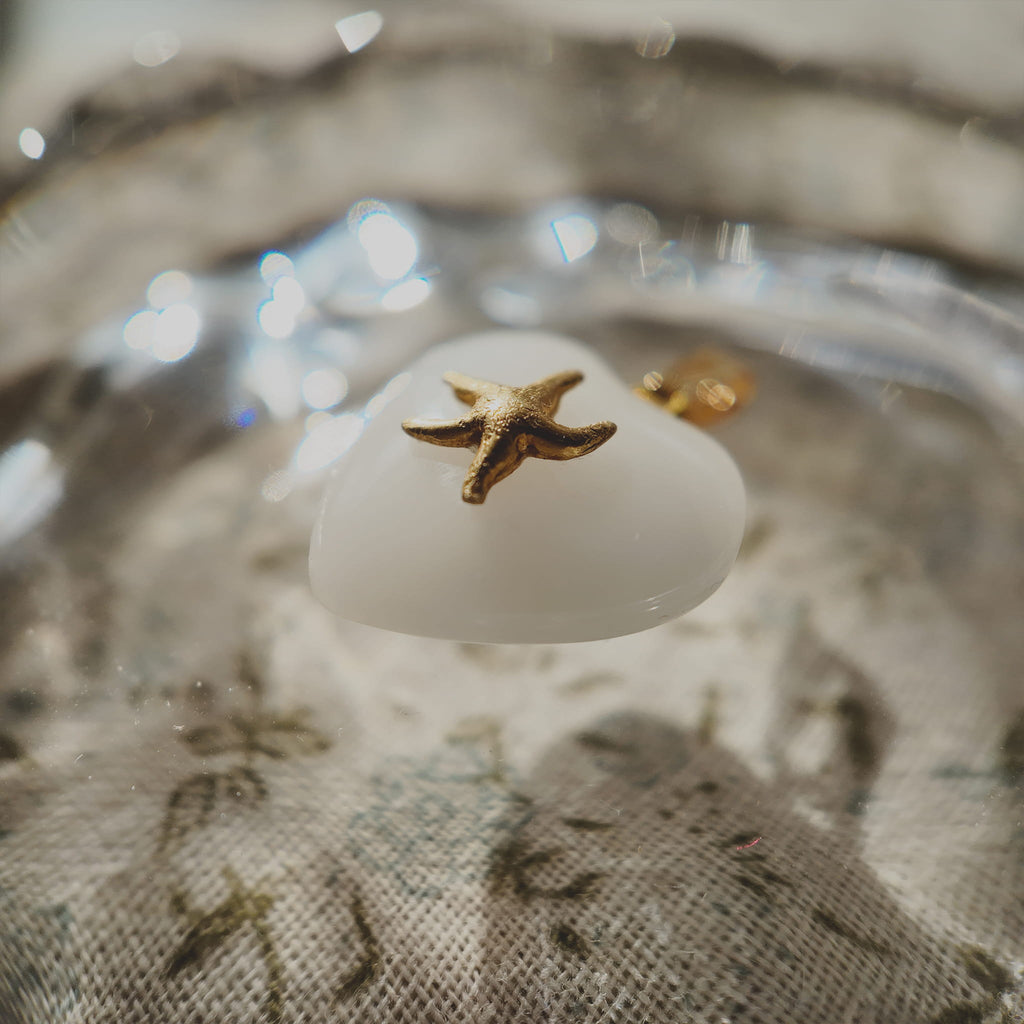 Side profile of the petite Milk Glass heart pendant, showing its form and the gold-plated bezel.