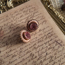 A macro shot detailing the sparkling, rose-pink rhinestone center and the creamy luster of the surrounding pearls on this piece of sweet, romantic jewelry.