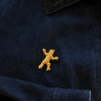 The quirky Van Wyk figural pin worn on a denim jacket, serving as a tiny, personal cheerleader and a unique piece of wearable art.