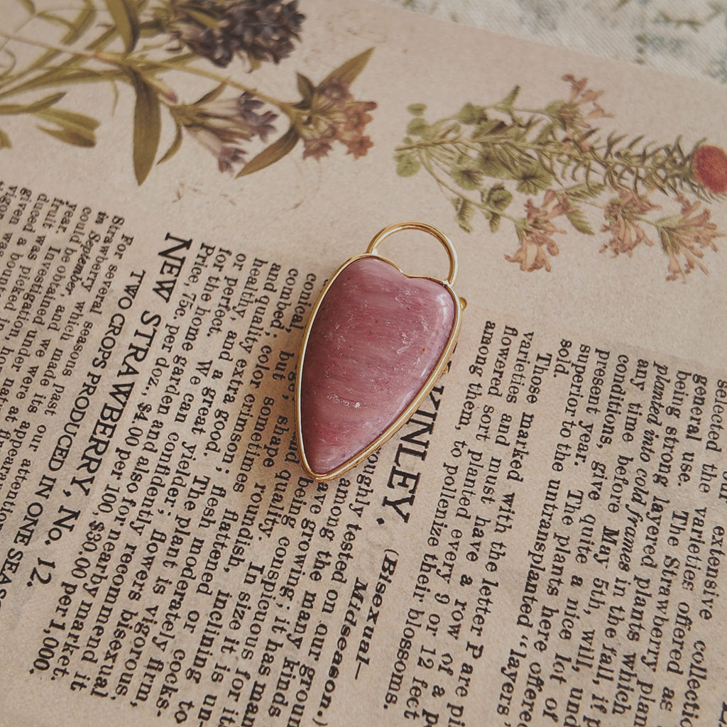 The reverse side of the upcycled Rhodochrosite charm, showcasing the clean bezel setting and the beautiful, natural banding of the stone.