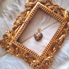 The handmade Strawberry Quartz Cupid charm styled on a piece of pink silk to emphasize its connection to romance and its identity as a perfect, sweet gift.