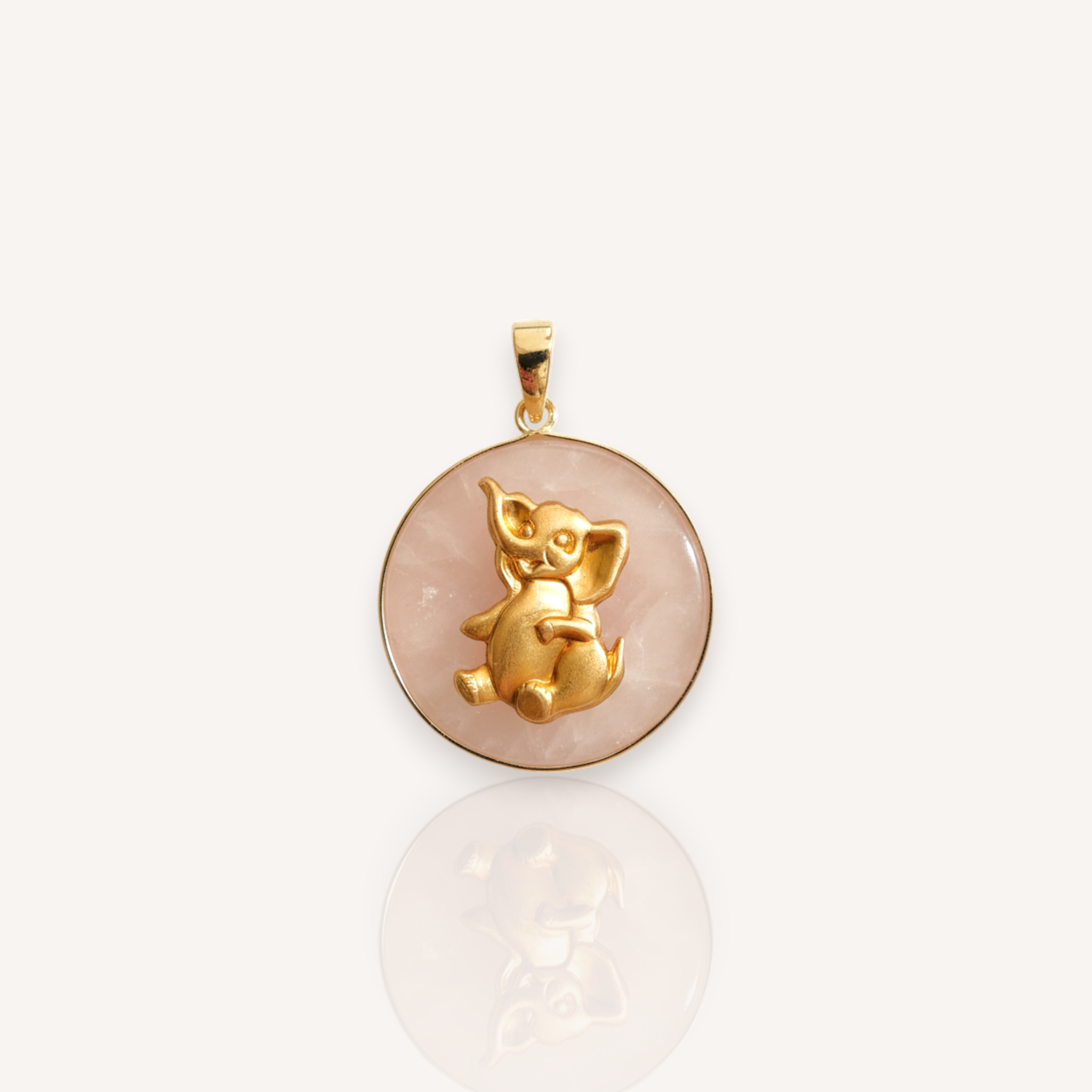  Front view of The Joyful Elephant pendant featuring a pale pink rose quartz medallion with a vintage brass sitting elephant.