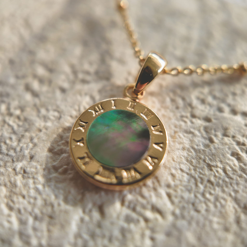 An angled view of the artisan charm, highlighting the intricate, 14k gold-plated filigree and the sparkling central cubic zirconia, with its gold-plated bail.