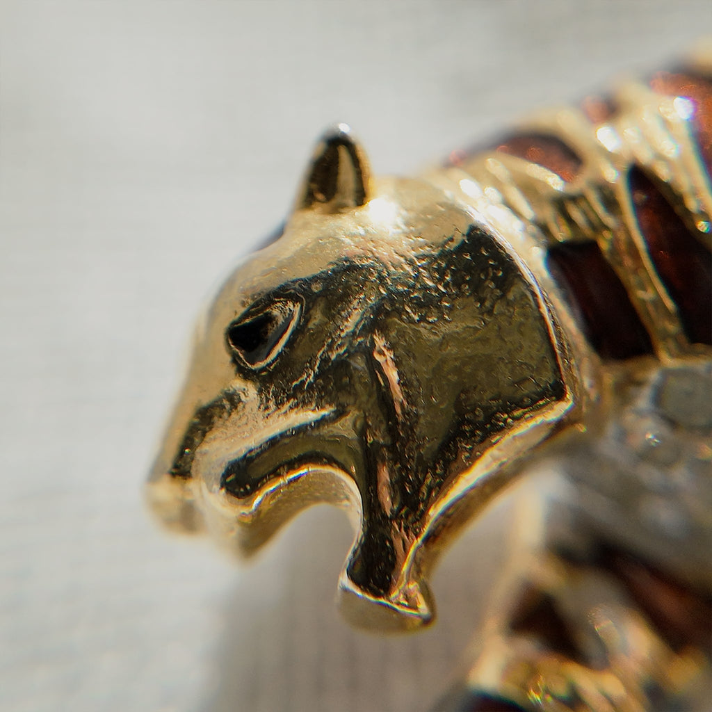A macro shot detailing the subtle, fiery glitter within the brown enamel and the brilliant sparkle of the clear crystal rhinestones on the tiger's belly.