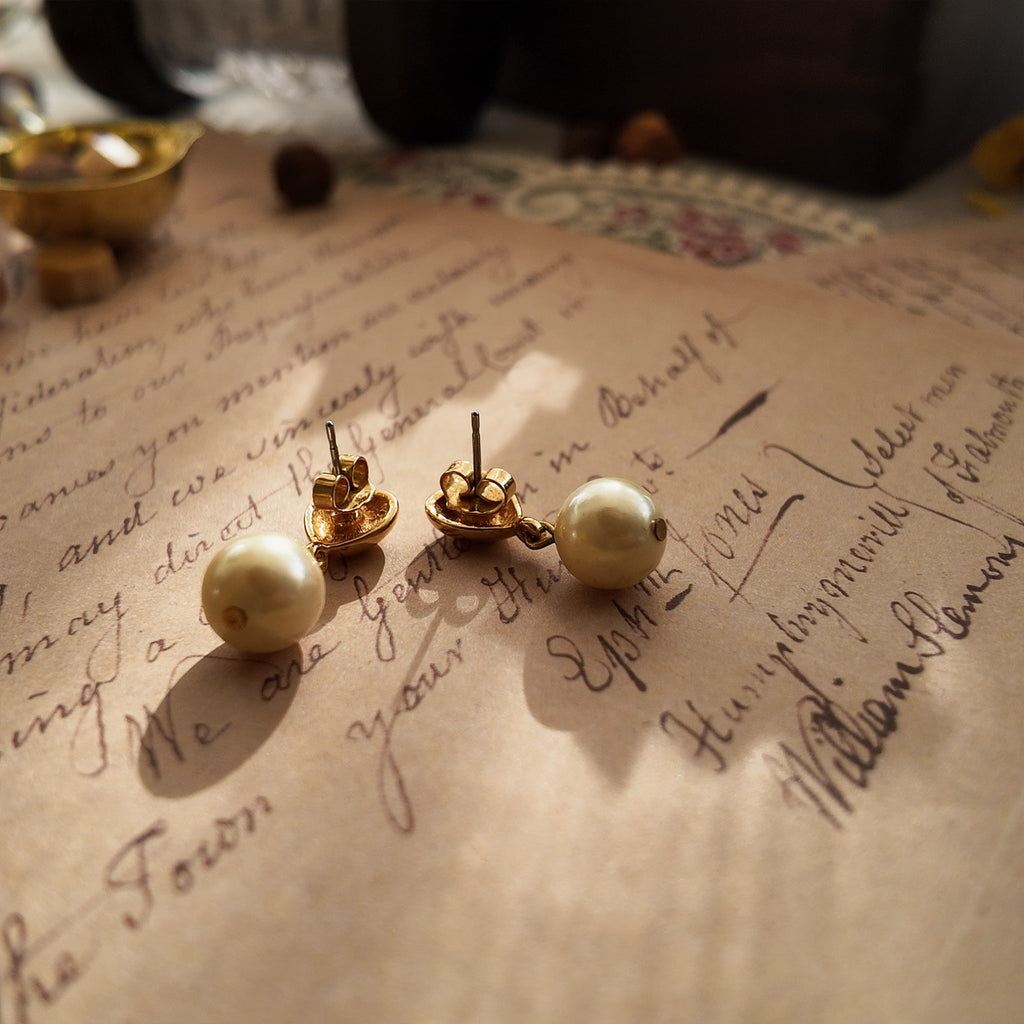 A macro shot honestly detailing the fine, hairline scratches on the gold-tone surface, a sign of this "well-loved" pair of vintage Avon earrings, sold as-is.