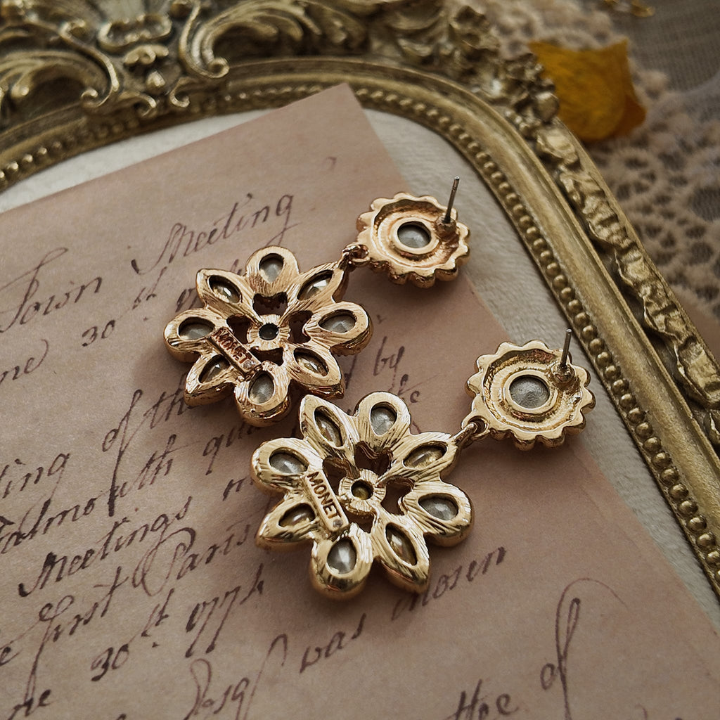 A close-up of the reverse side, showing the authentic "MONET" signature on the clip of the vintage gold-plated floral earrings.