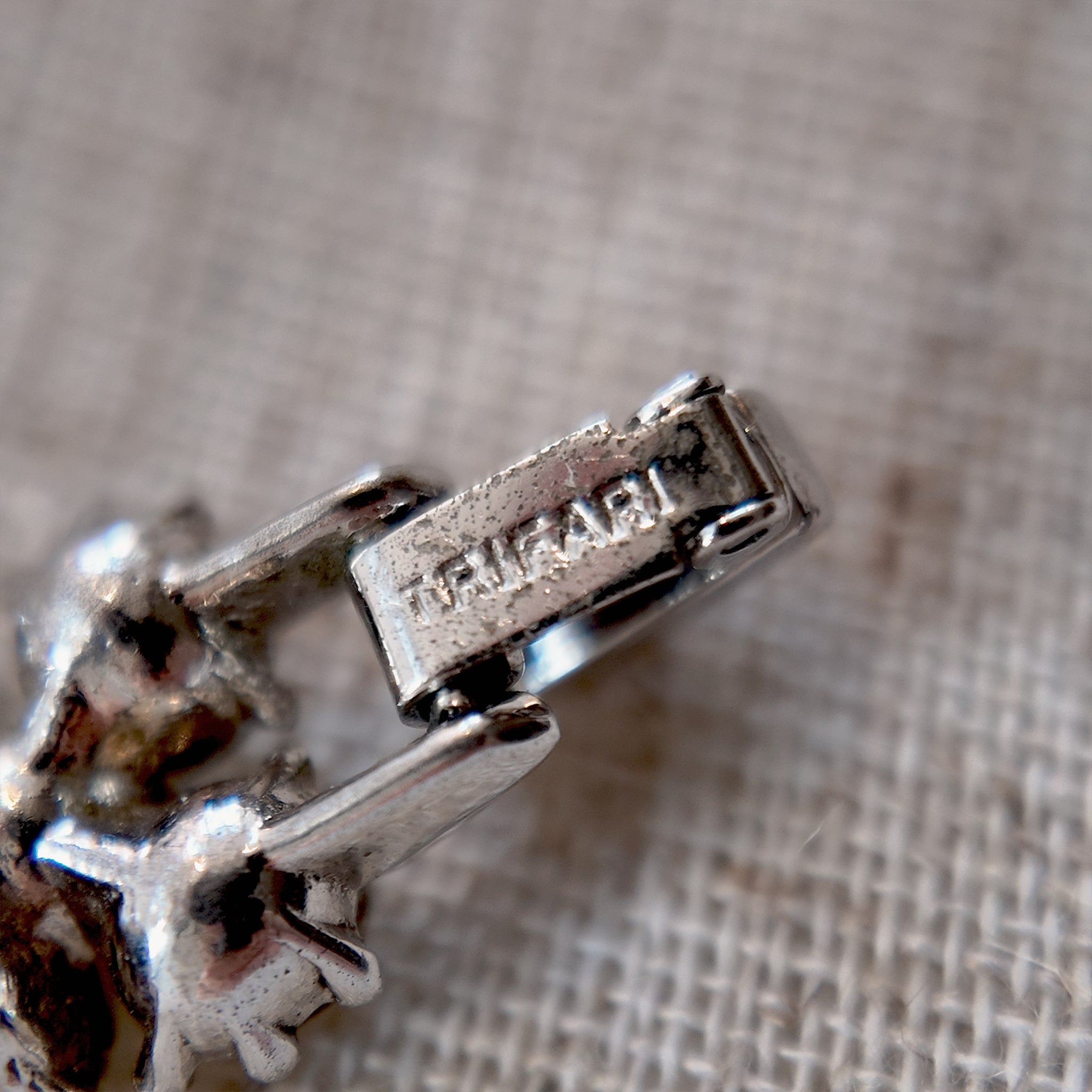 A close-up of the authentic "TRIFARI" signature on the clasp, also honestly showing the minor surface wear on the back of the vintage bracelet.