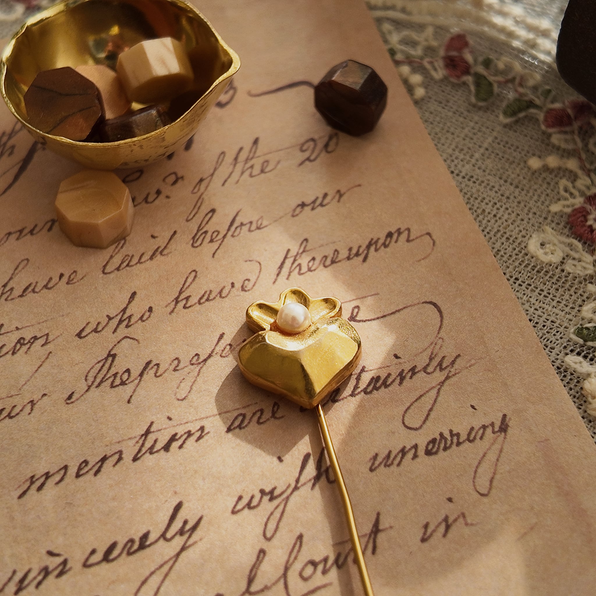 An angled view of the matte gold heart brooch, highlighting its smooth, non-reflective surface and the gentle sheen of the crowning pearl.