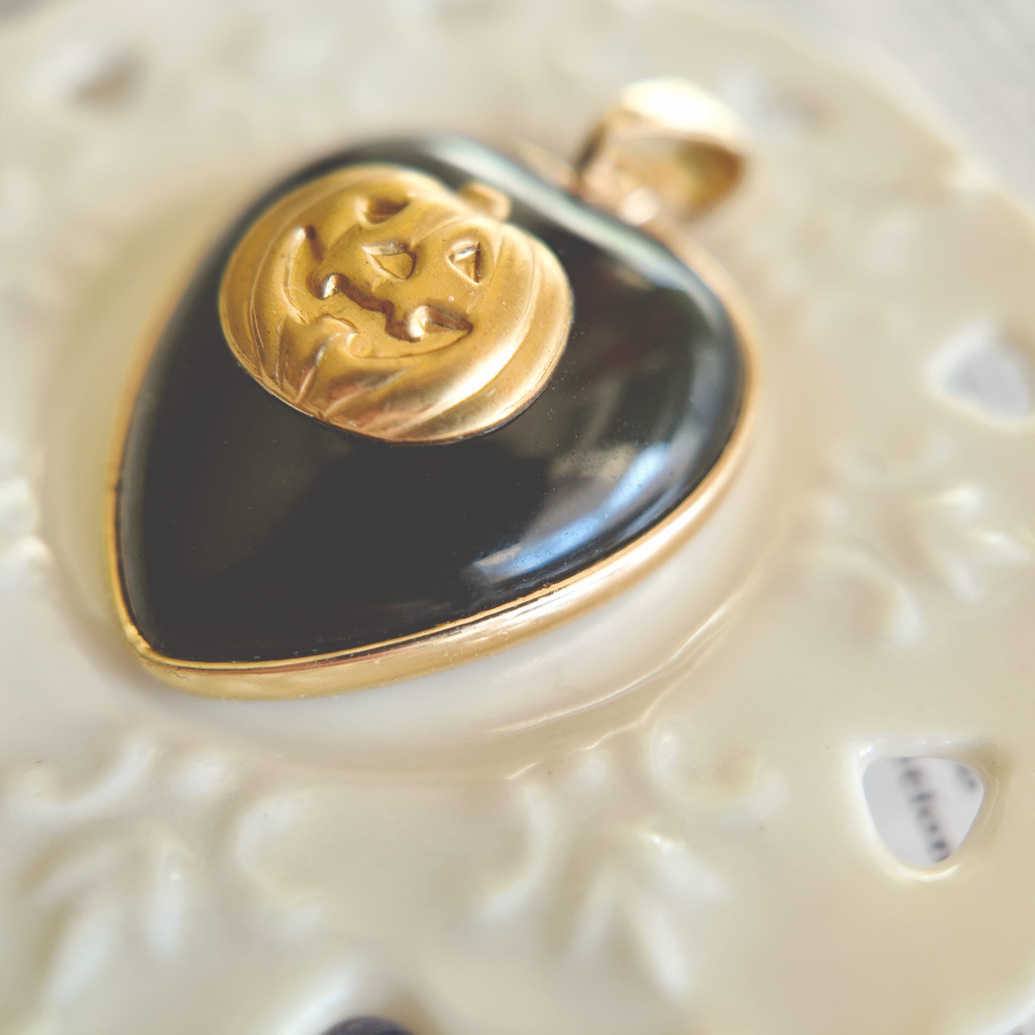 Side profile of the black onyx heart pendant, showing its solid weight and the gold-plated bezel.