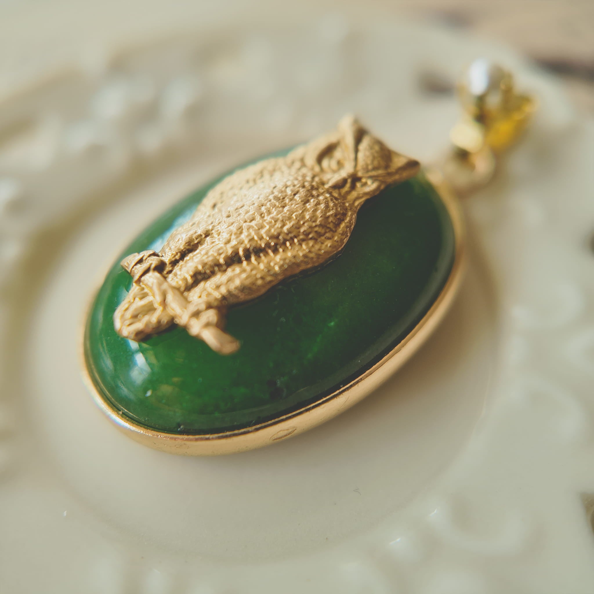 Side profile of the classic oval green jade pendant, showing its solid and grounding feel with gold-plated bezel.