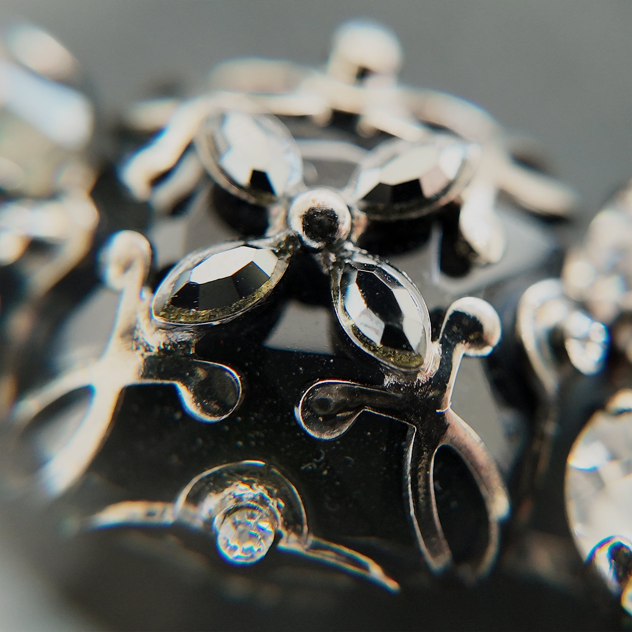 A macro shot detailing the brilliant sparkle of the black diamond crystals and the "poetic decay" of the antiqued filigree on this collectible Sorrelli bracelet.