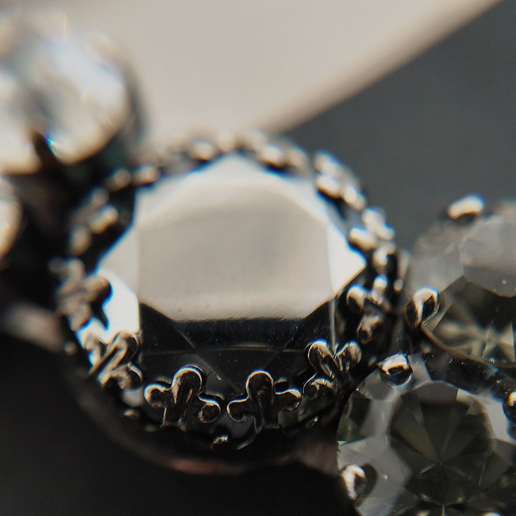 A macro shot detailing the brilliant sparkle of the black diamond crystals and the "poetic decay" of the antiqued filigree on this collectible Sorrelli bracelet.
