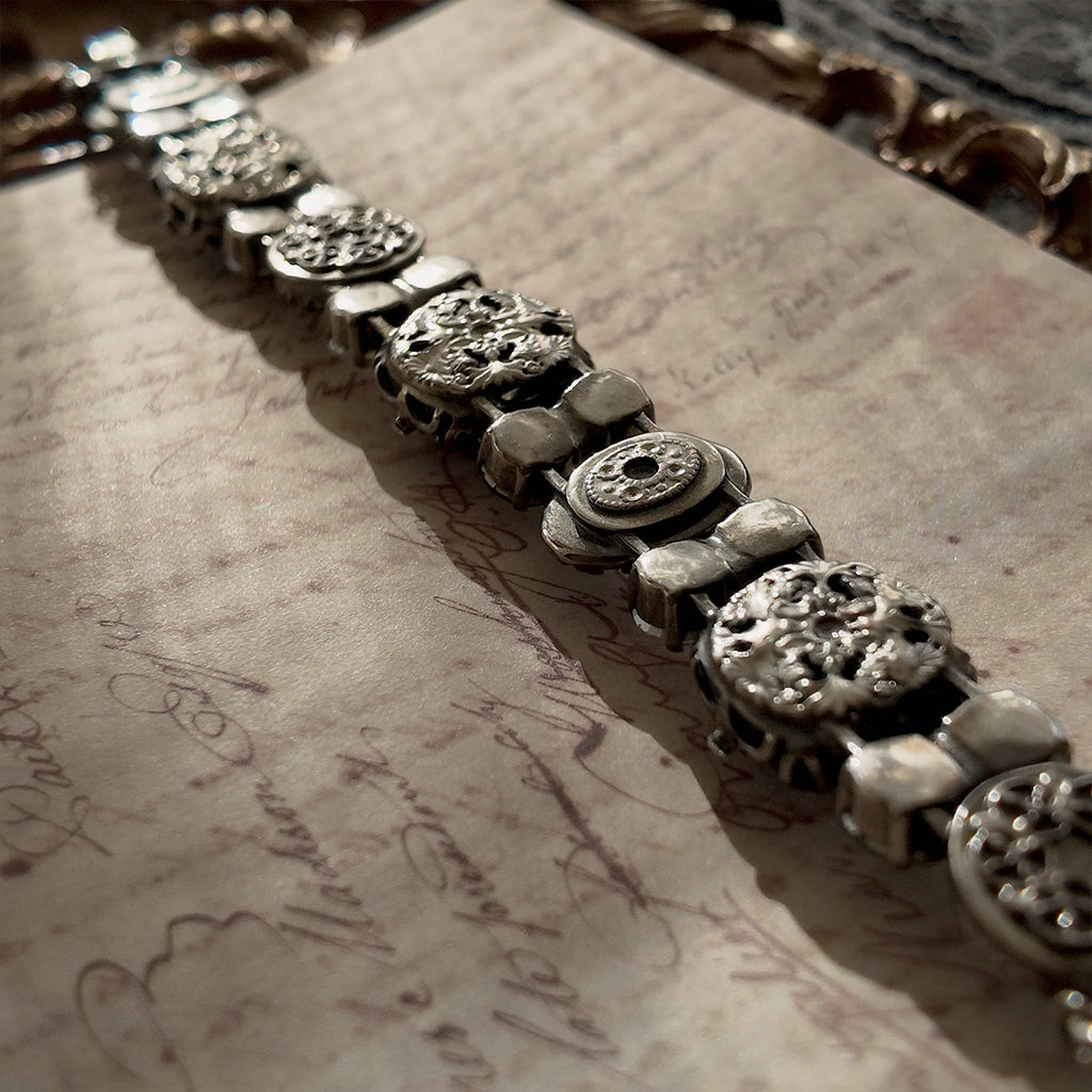 A close-up of the authentic "Sorrelli" signature hang tag on the back of the antiqued silver-tone vintage statement bracelet.