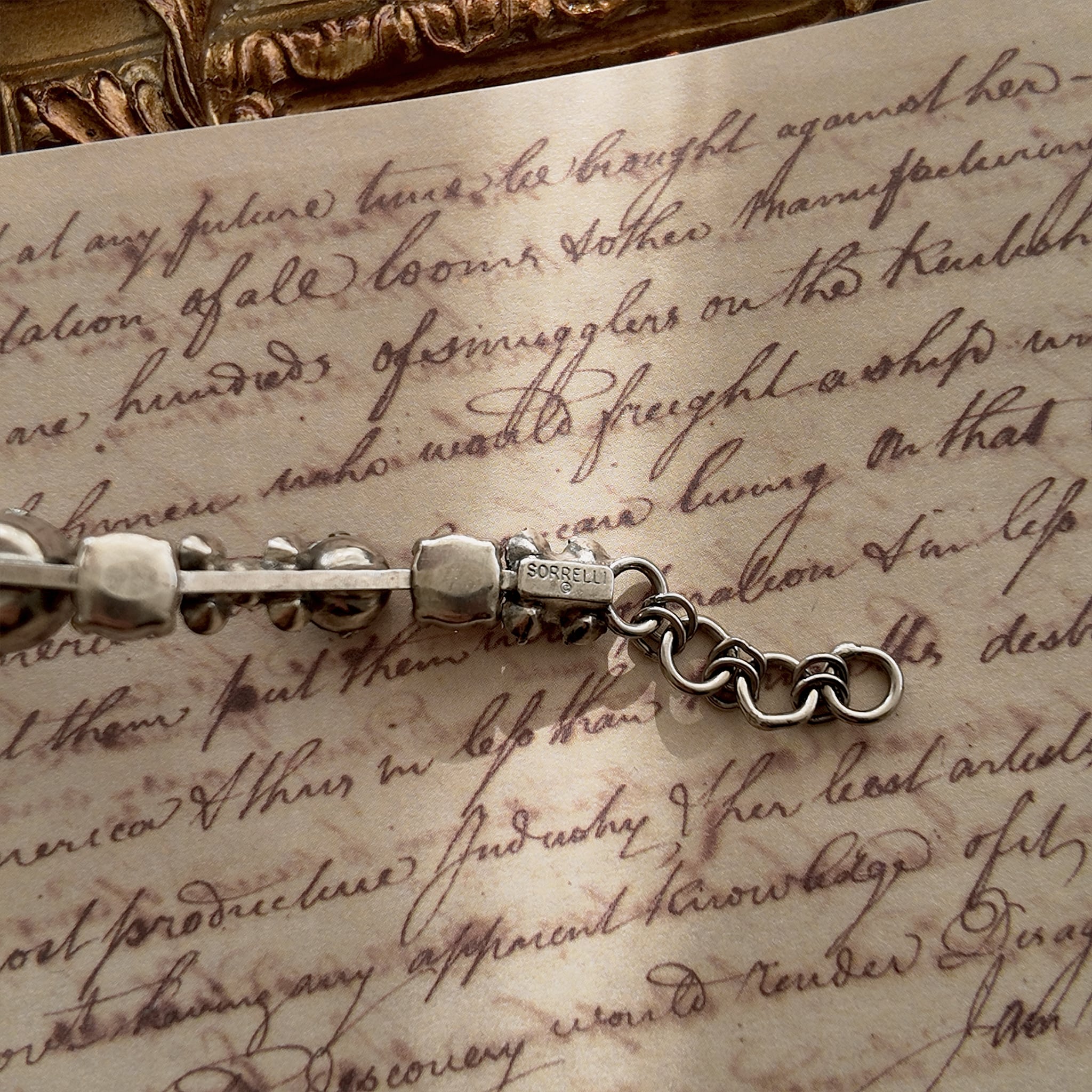 A close-up of the authentic "Sorrelli" signature hang tag on the back of the vintage pink and black crystal bracelet.