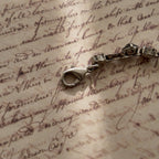 A close-up of the authentic "Sorrelli" signature hang tag on the back of the vintage pink and black crystal bracelet.