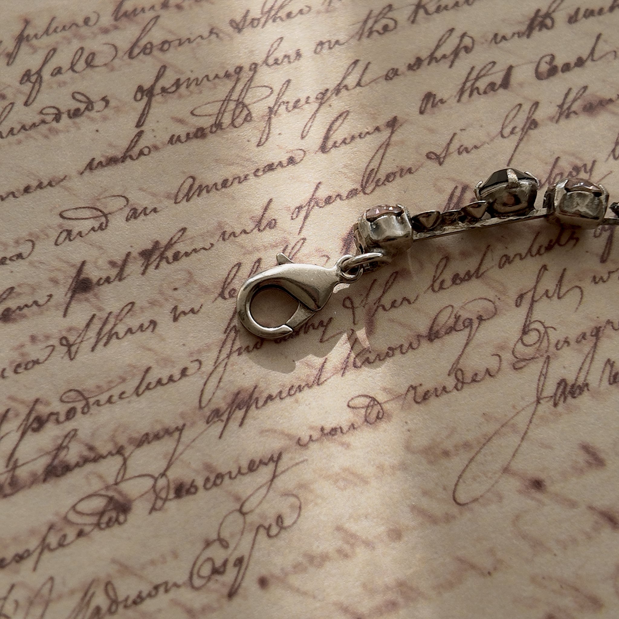 A close-up of the authentic "Sorrelli" signature hang tag on the back of the vintage pink and black crystal bracelet.