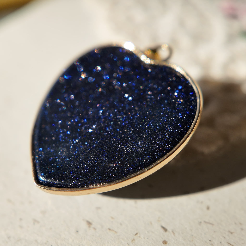 A macro shot capturing the thousands of tiny, star-like sparkles within the polished blue goldstone of the "Galactic Faith" necklace.