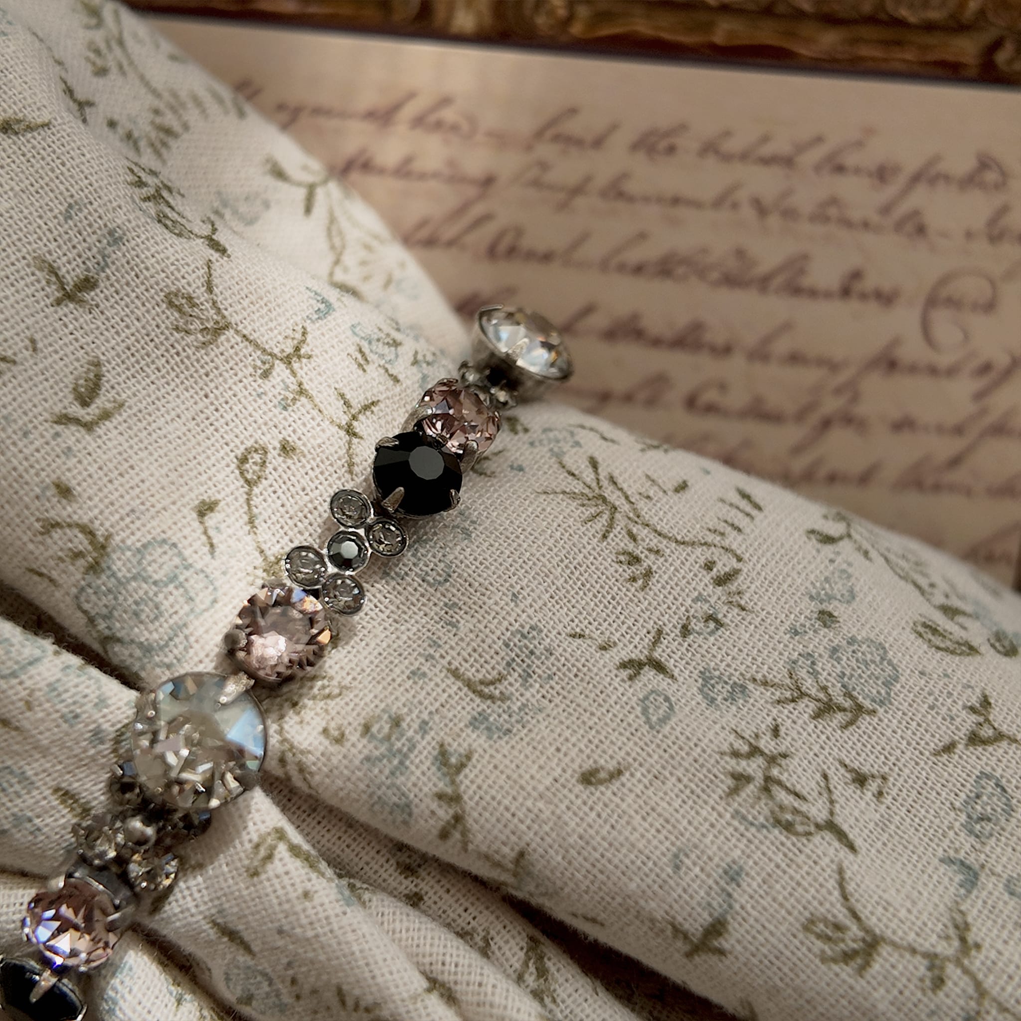 A macro shot detailing the brilliant sparkle of the candy-pink and jet-black Swarovski crystals on this piece of Whimsigoth-style jewelry.