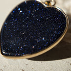 The "Galactic Faith" cross necklace styled on a dark velvet background to emphasize its celestial, starlit aesthetic and its identity as a piece of artisan-made jewelry.