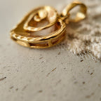 The size of "The Sunset Vortex" small gold pendant compared to show its delicate, potent scale.