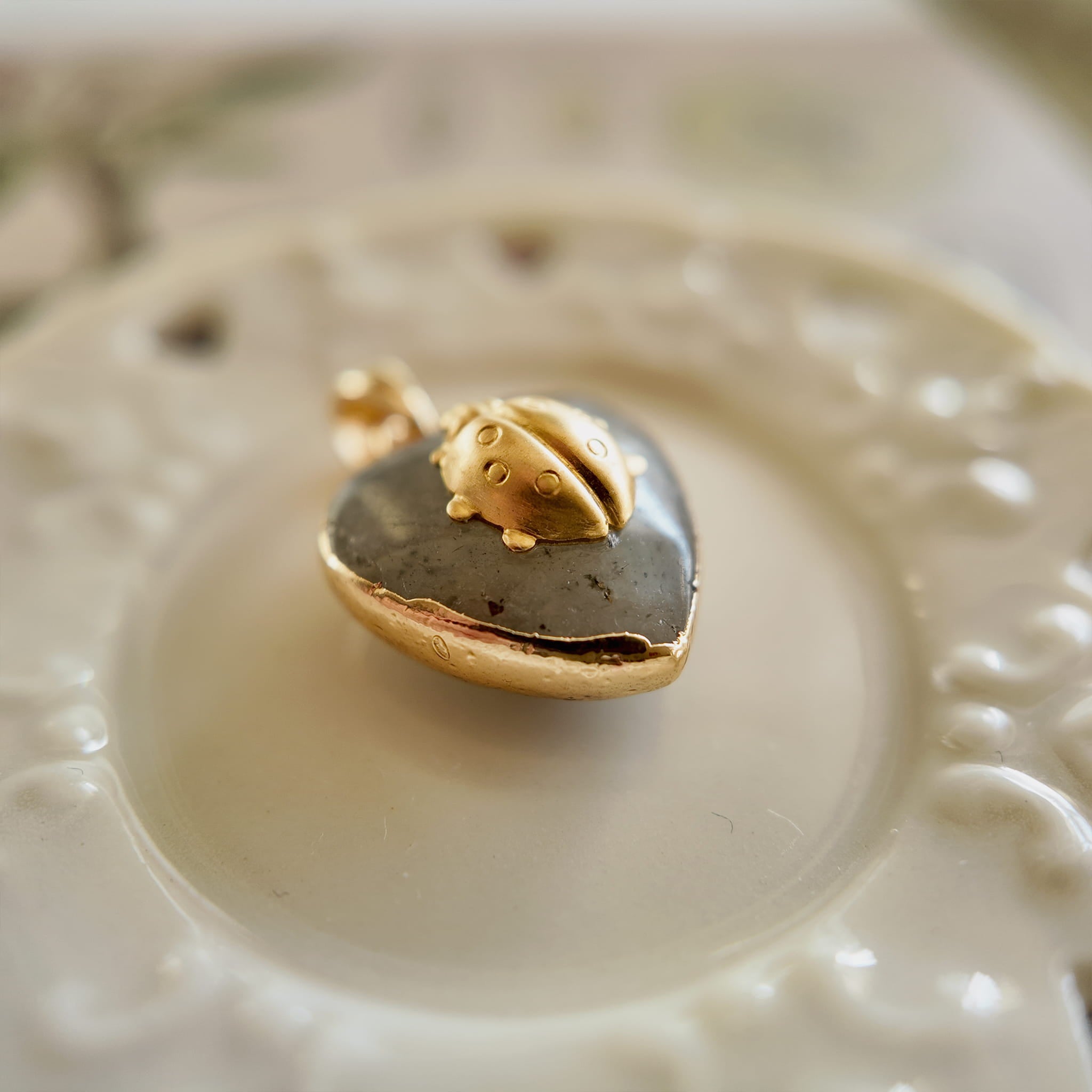 Side profile of the micro-miniature heart pendant showcasing its thinness and the gold-plated bezel.