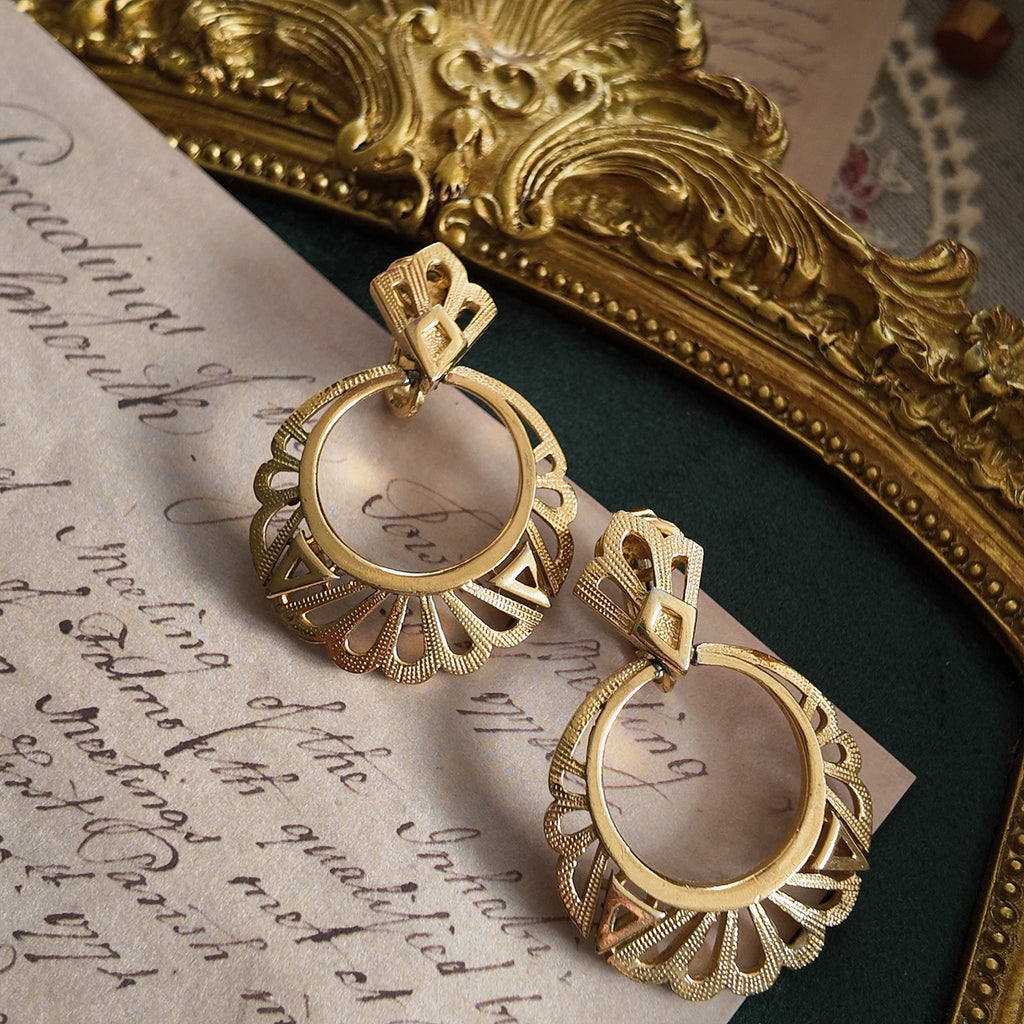 A pair of "The Free Spirit" vintage Trifari dangle earrings, featuring an intricate gold filigree stud and a dangling openwork geometric ring.