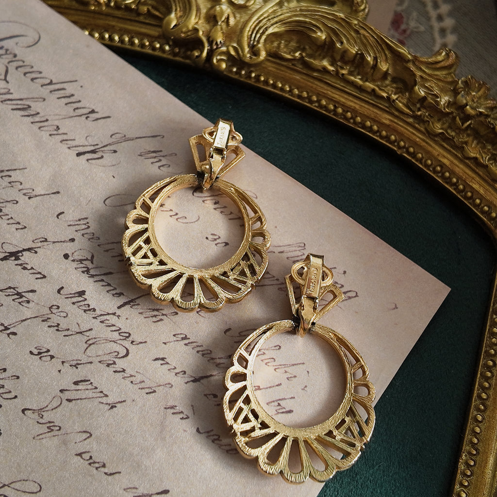 A close-up of the authentic "TRIFARI" signature with the crown logo on the back of the vintage gold-plated clip-on earrings.