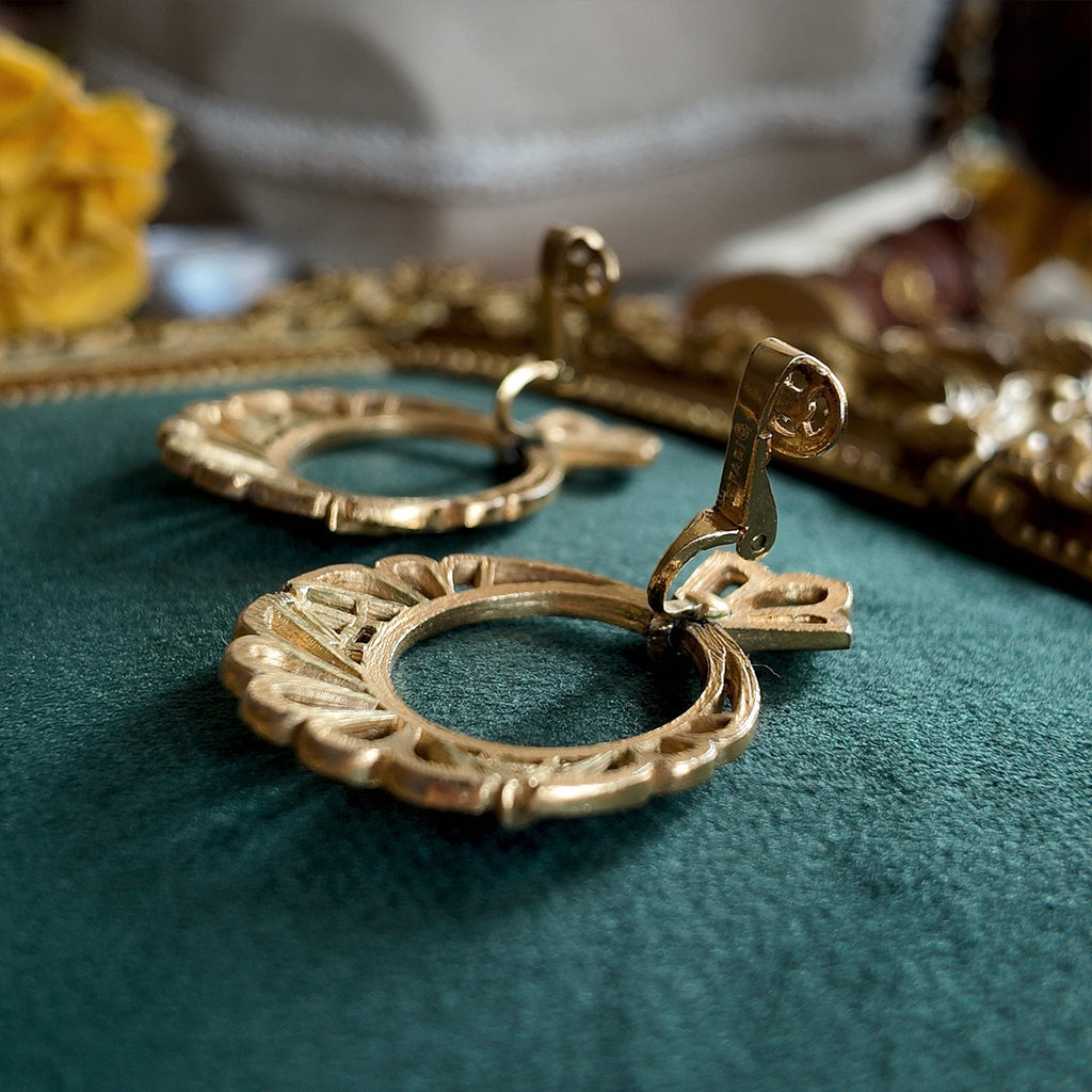 A close-up of the authentic "TRIFARI" signature with the crown logo on the back of the vintage gold-plated clip-on earrings.