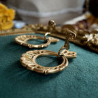 A close-up of the authentic "TRIFARI" signature with the crown logo on the back of the vintage gold-plated clip-on earrings.