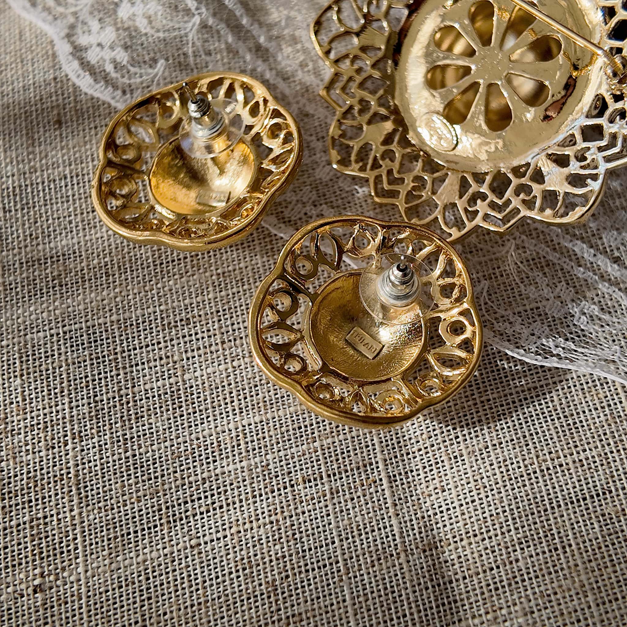 A macro shot detailing the intricate, lace-like filigree craftsmanship on the brim of the Trifari hat brooch, a hallmark of the brand's 1960s high-quality production.