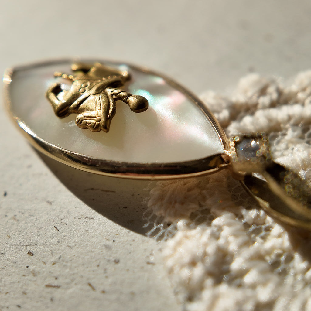 An angled view of the "Ticket to Dreamland" artisan pendant, highlighting the layered construction of the upcycled vintage brass horse and MOP components.