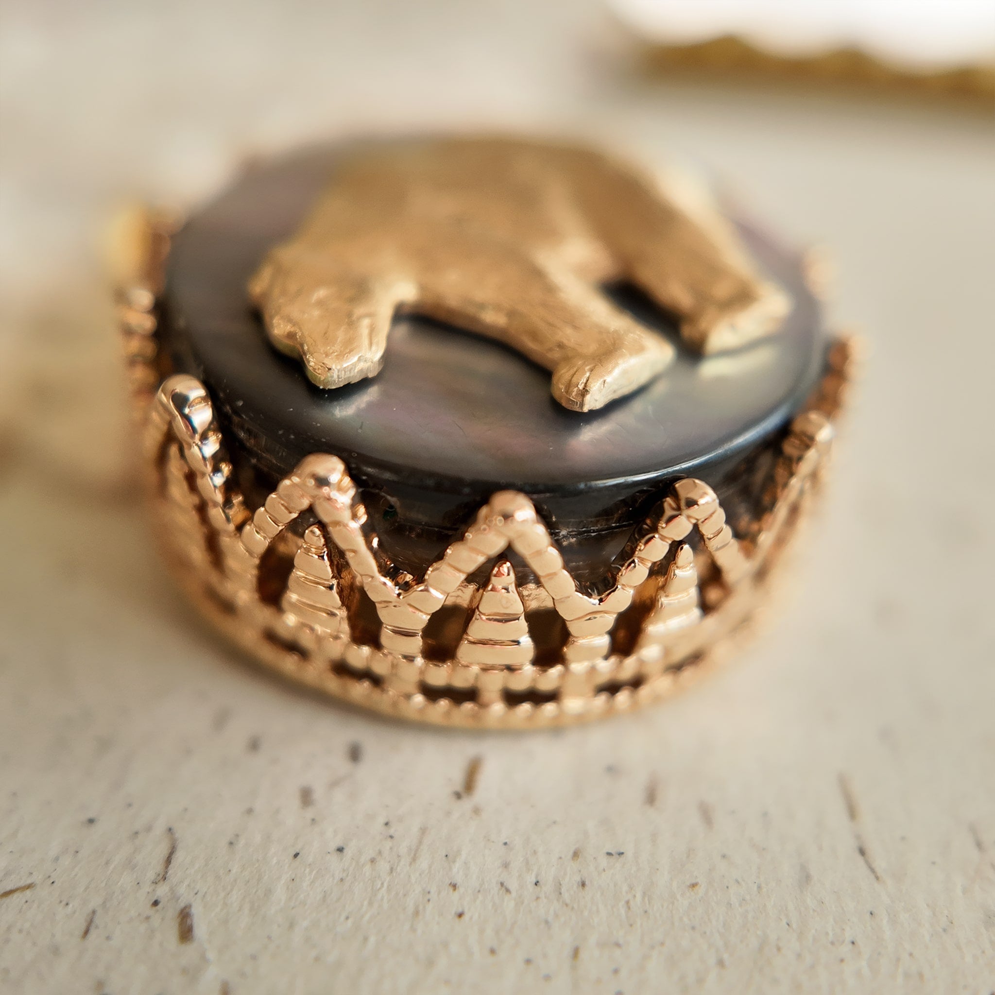 An angled view of the "Bear Who Dreamed of Stars" artisan pendant, highlighting the layered construction of the upcycled vintage brass and natural shell components.