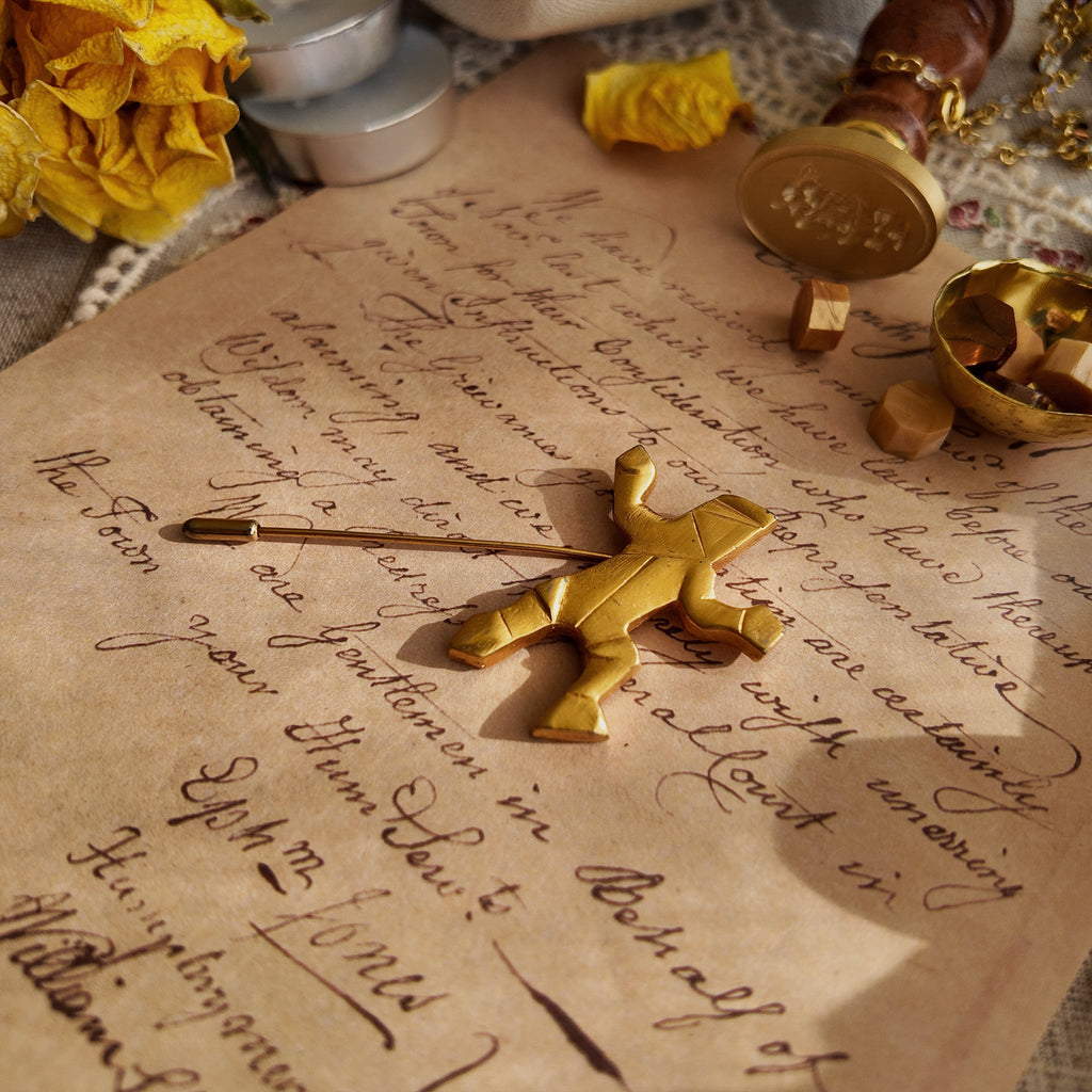 An angled view of the modernist gold brooch, highlighting the charming, ambiguous motion of the Sisyphus-like figure—is he dancing or struggling?