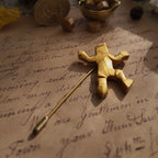 An angled view of the modernist gold brooch, highlighting the charming, ambiguous motion of the Sisyphus-like figure—is he dancing or struggling?