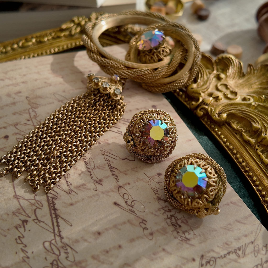 A detailed view of the matching Vendôme earrings, highlighting the woven gold texture and the large, central Aurora Borealis crystal with its otherworldly fire.