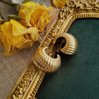 An angled view of the gold sculptural earrings, highlighting the beautiful, volumetric "croissant" twist that defines this classic piece of 70s jewelry design.