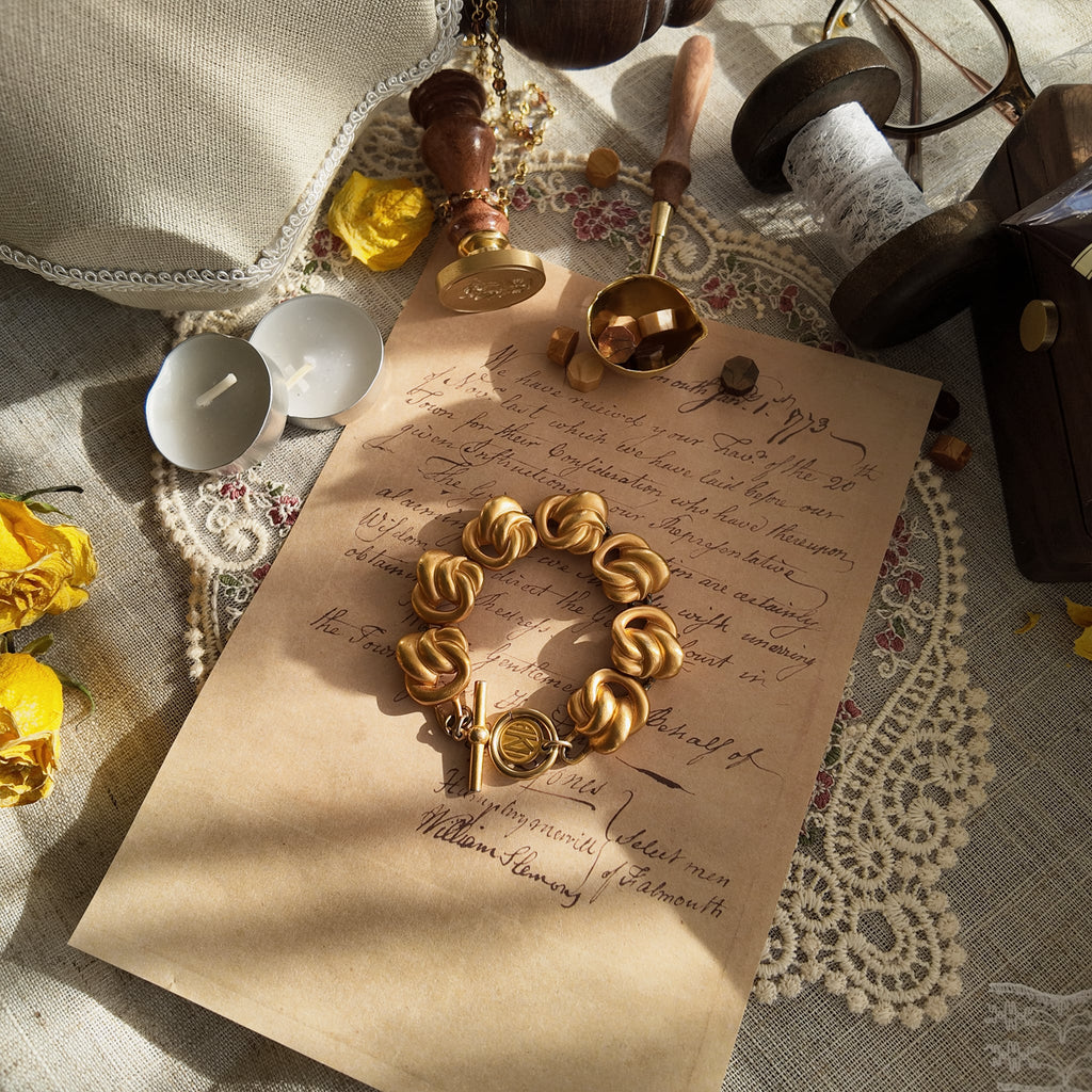A close-up of the Anne Klein Power Dressing bracelet, showcasing the sculptural, architectural knot links and the sophisticated, non-reflective matte gold finish.