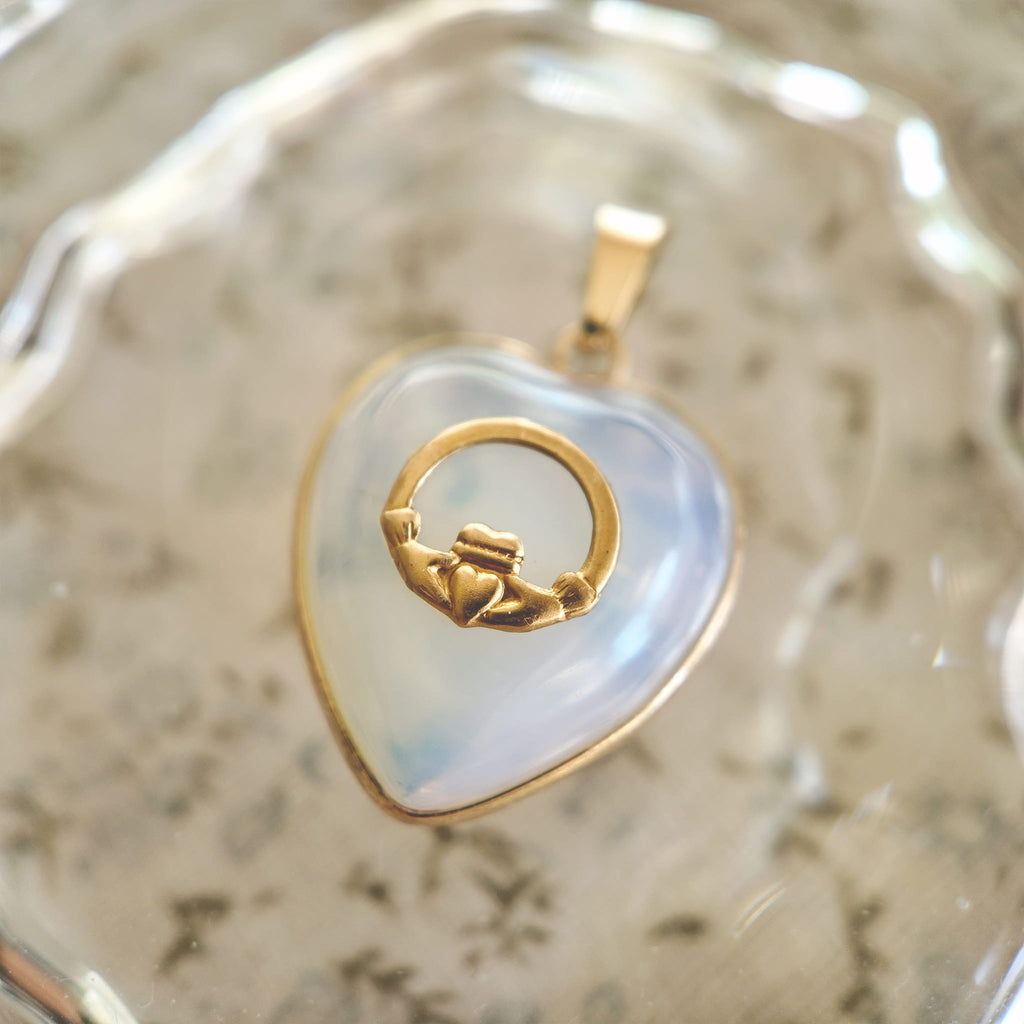 Close-up detail of the vintage brass hands holding a tiny heart, a Claddagh-style symbol of unity.