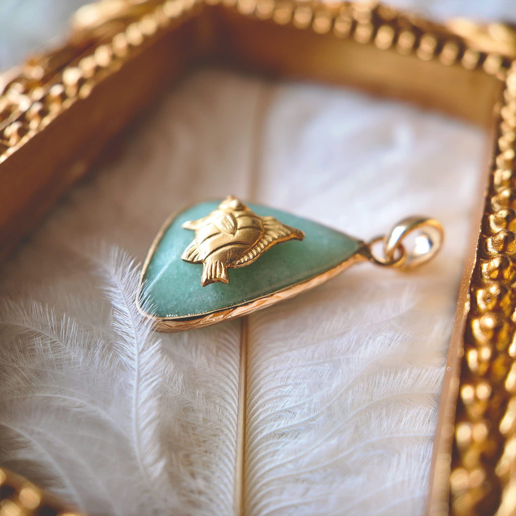 An angled view of the artisan charm, highlighting the lively, detailed sculpting of the brass fish and the smooth, gold-plated bail.
