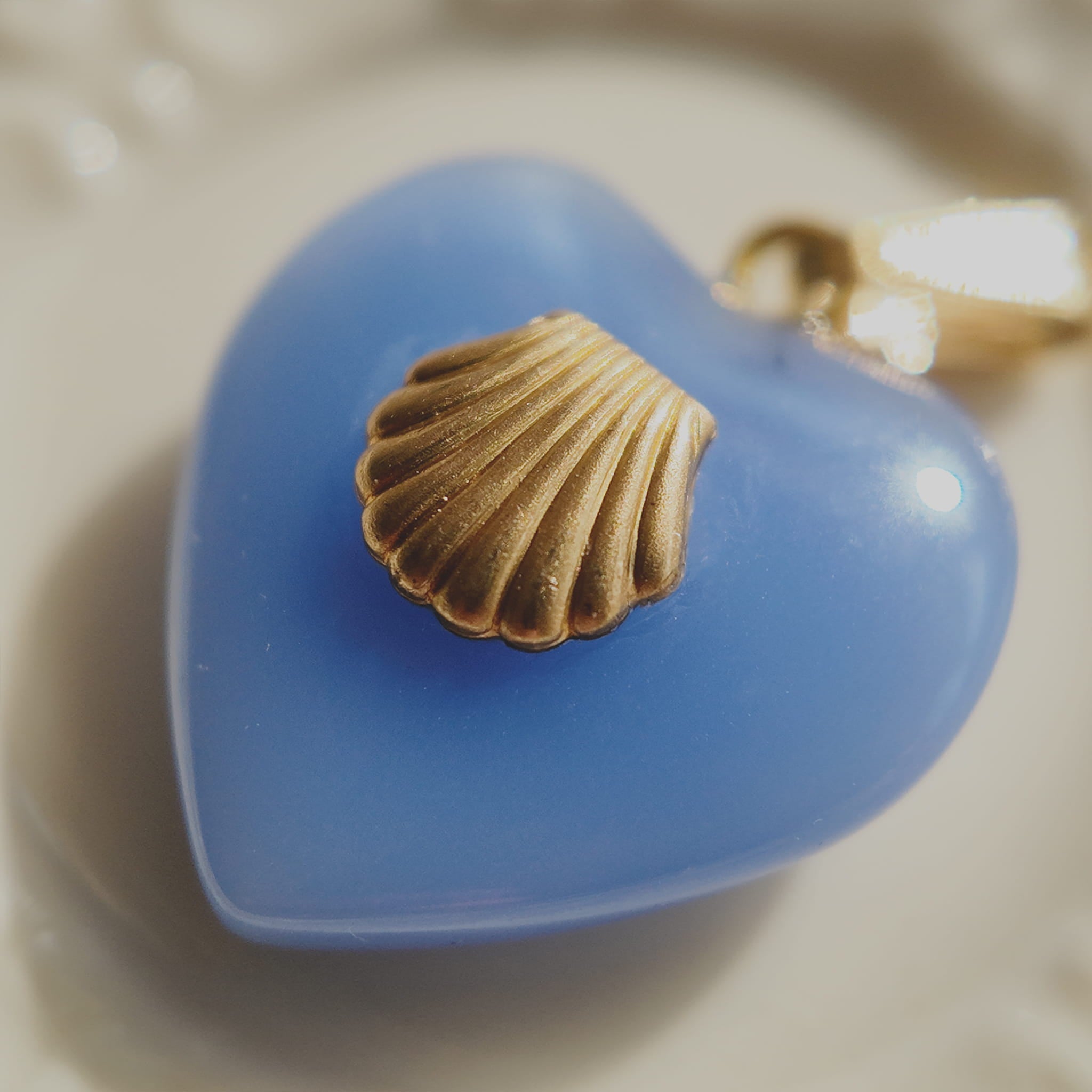 Close-up detail of the detailed and textured vintage brass scallop shell, showing warm patina against the cool blue background.