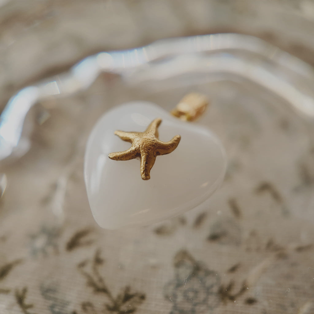Close-up detail of the detailed and textured vintage brass starfish, sitting securely on the milk glass.