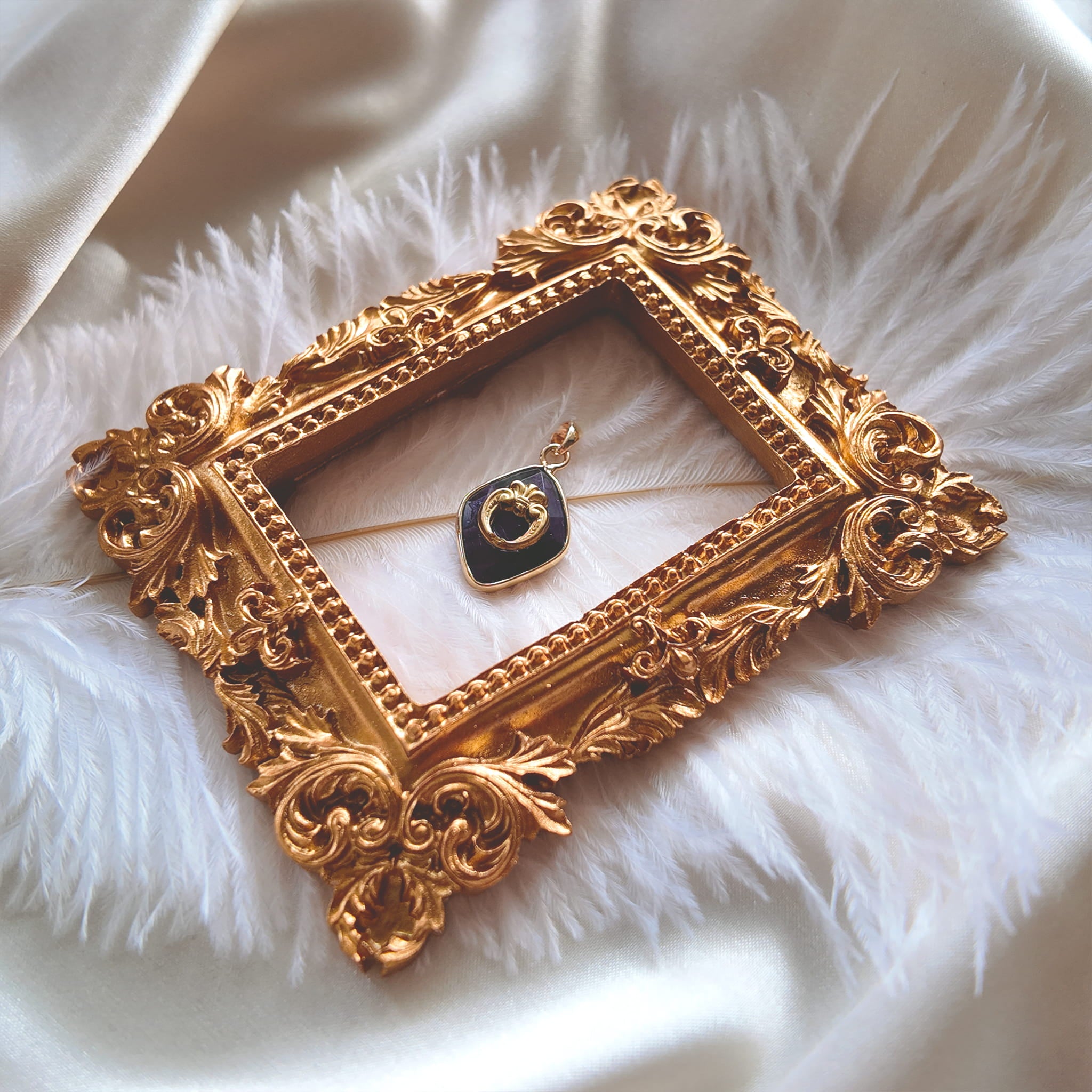 An angled view of the artisan charm, highlighting the intricate, symmetrical openwork of the brass filigree wreath and the elegant, gold-plated bail.