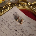 The vintage Avon Christmas earrings styled on a holiday card to emphasize their identity as a piece of pure, nostalgic Christmas spirit and a perfect festive gift.