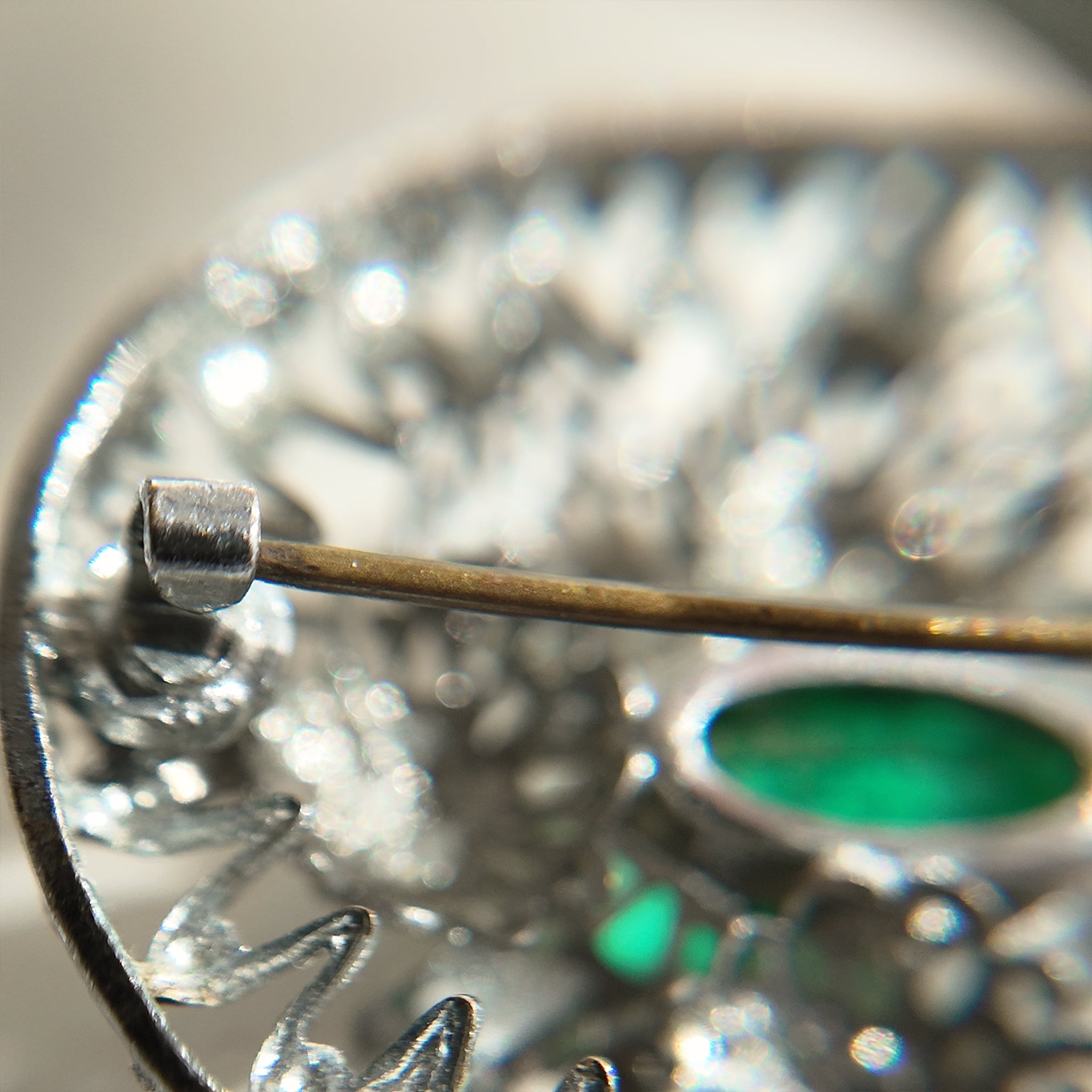 A close-up of the back of a silver cloisonné brooch under high magnification, showcasing the details of the back pin and its joints.