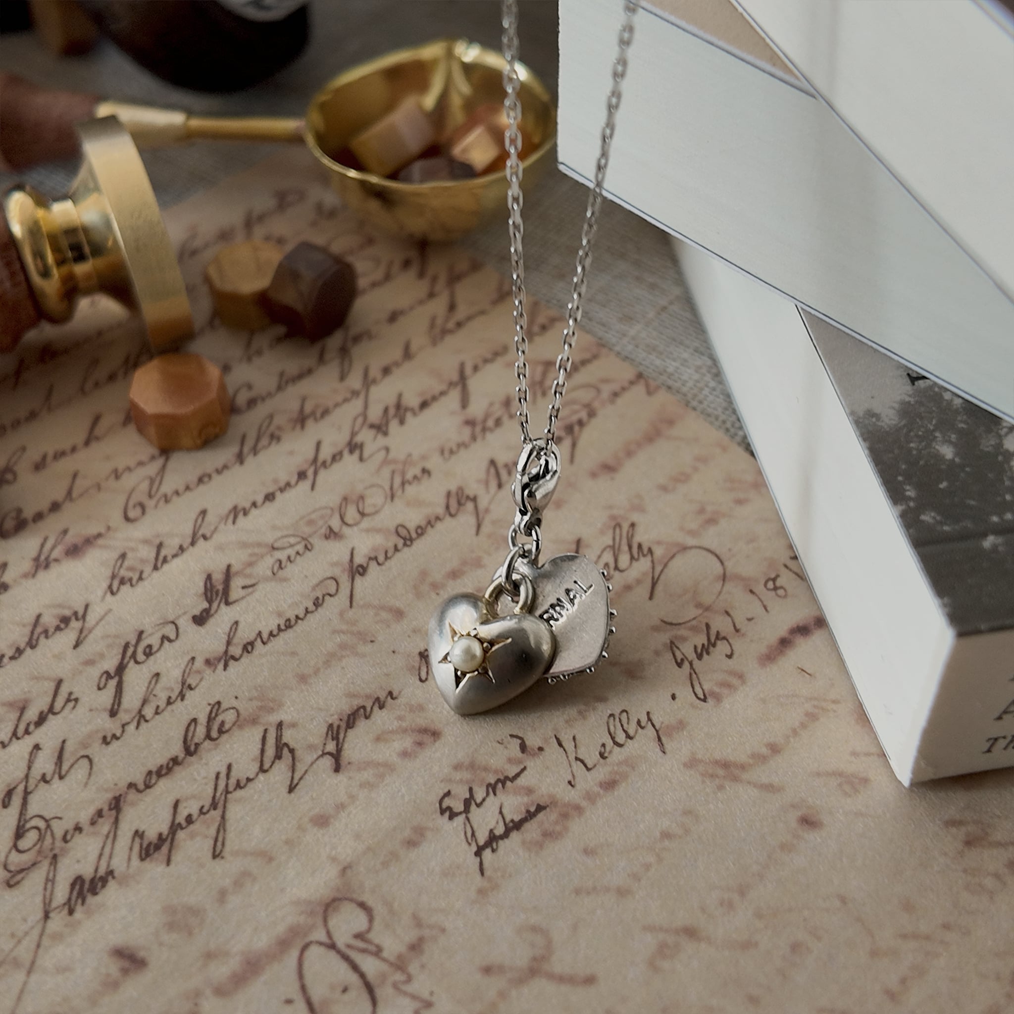 The "Vow" sterling silver necklace styled on a handwritten love letter to emphasize its identity as the perfect sentimental gift for a soulmate or anniversary.